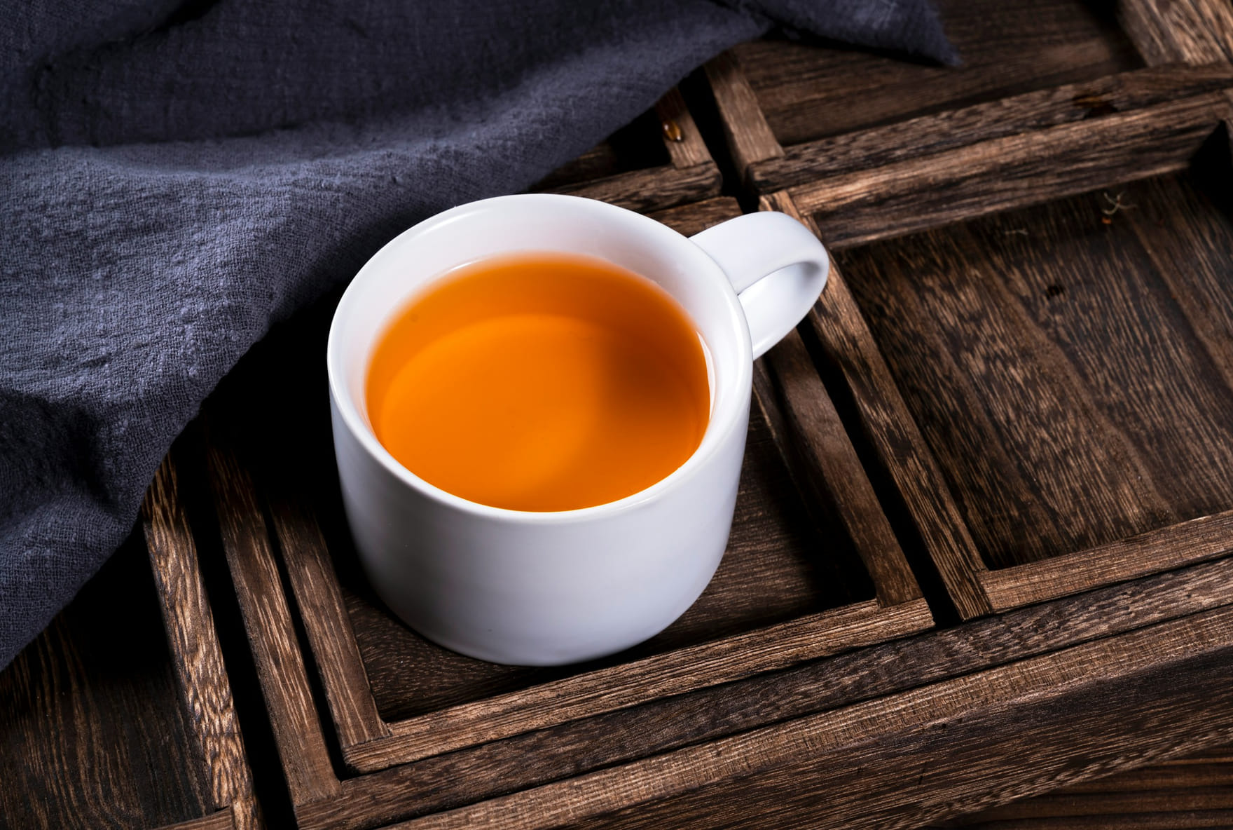 Tasse mit Tee auf einem dunklen Holztablett